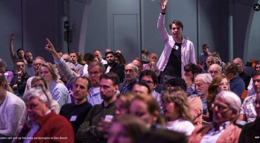 Audience at a Volt congress raising their hands during a session